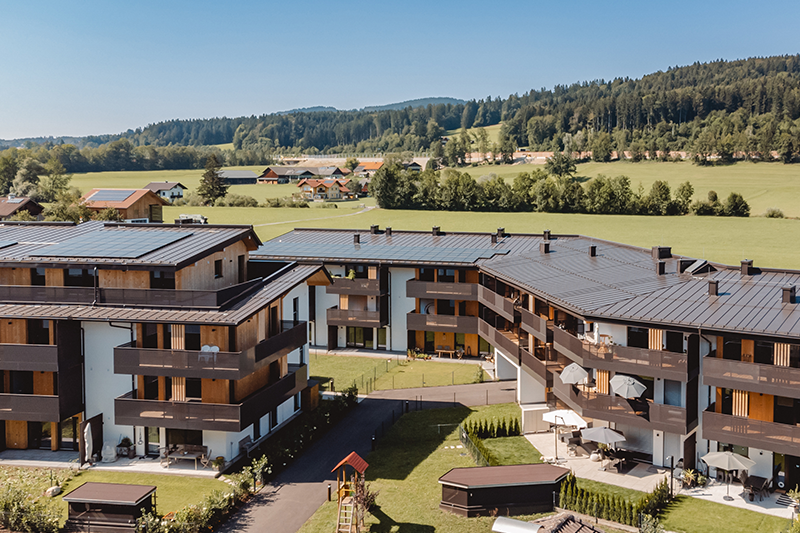 Luftaufnahme der Wohnanlage Wohnen am Sagergut in Thalgau mit nachhaltiger Holzarchitektur und Blick auf die umliegende Naturlandschaft.
