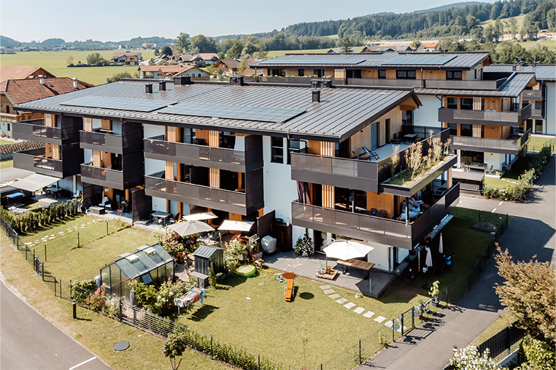Luftaufnahme der Wohnanlage Wohnen am Sagergut in Thalgau mit großzügigen Gärten, Balkonen und nachhaltiger Holzarchitektur.