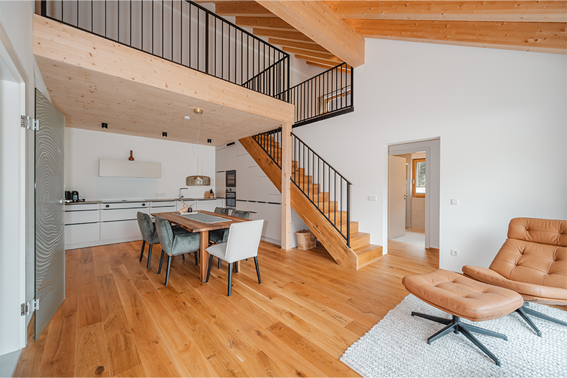 Offener Wohn- und Essbereich im Baron Tower Saalbach mit Galerie, sichtbaren Holzelementen und hochwertiger Ausstattung.