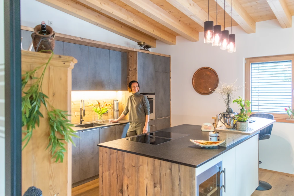 Moderne Wohnküche im Wohnbauprojekt Bischofshofen mit sichtbarer Holzdecke und Kücheninsel