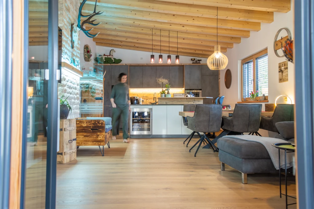 Moderner Wohn- und Essbereich im Wohnbauprojekt Bischofshofen mit offener Küche und sichtbarer Holzdecke